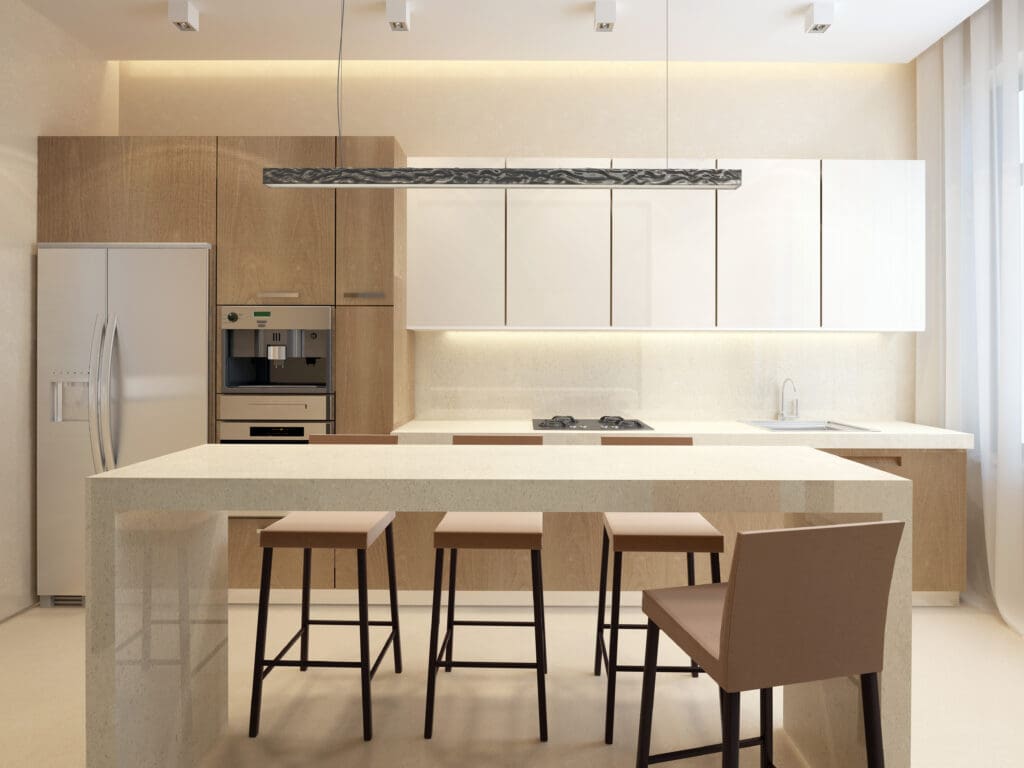 A modern kitchen with light beige tones featuring a large island with three bar stools, a built-in oven, and a refrigerator. The space includes ample cabinetry, a sleek light fixture above the island, and minimalistic design elements.